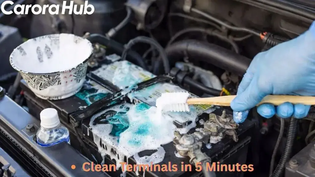 A person using a baking soda and water paste to scrub away white acidic corrosion from car battery terminals with a toothbrush.