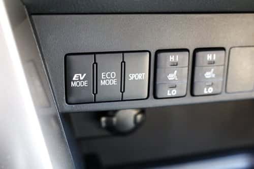 A close-up view of the center console buttons in a modern hybrid car.