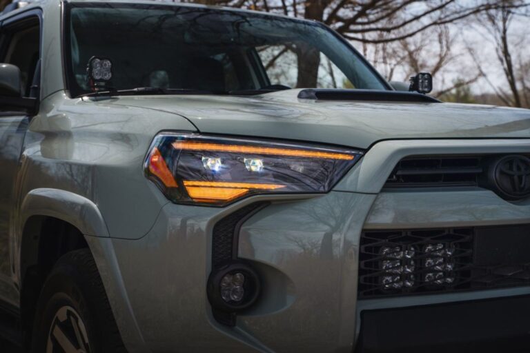 LED headlight bulbs resting near a Toyota 4Runner in a bright garage.