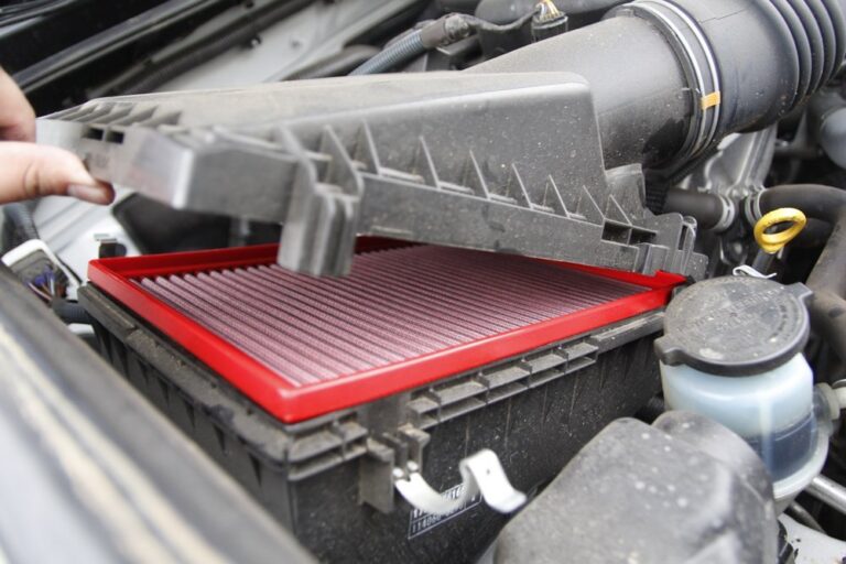 Person holding air filter and wrench next to open hood of Toyota 4Runner