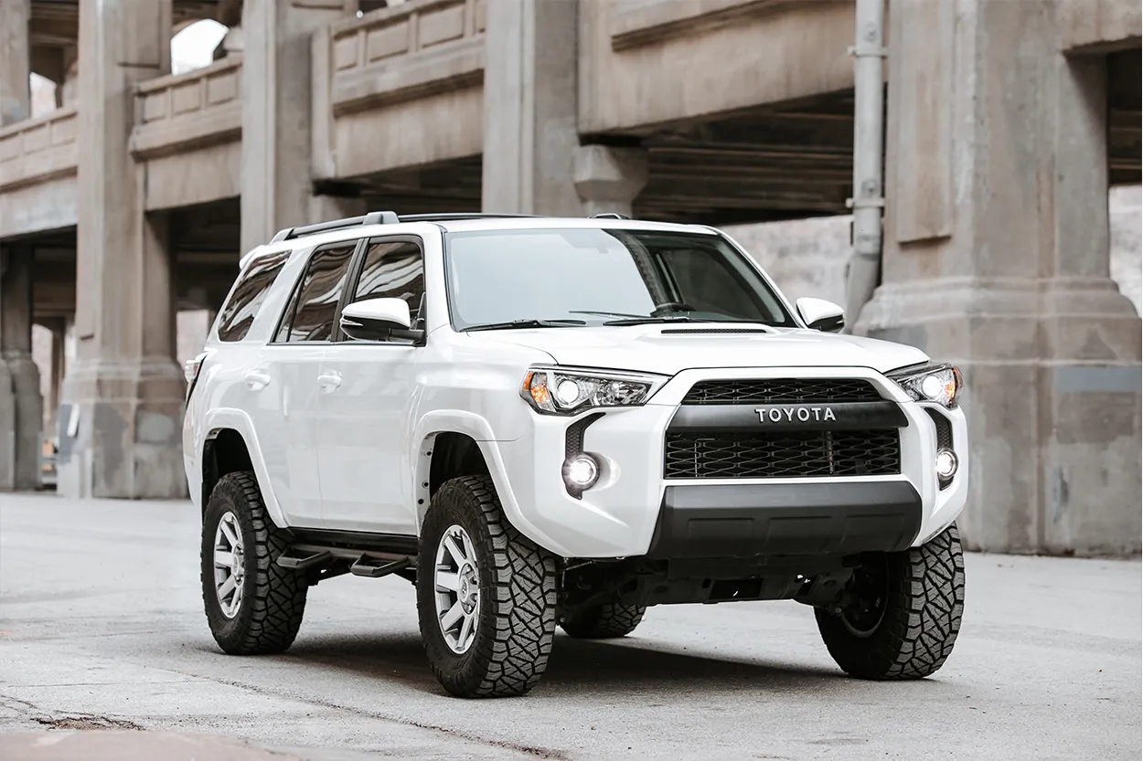 Person researching Toyota 4Runner lift kits on a laptop in a well-organized garage