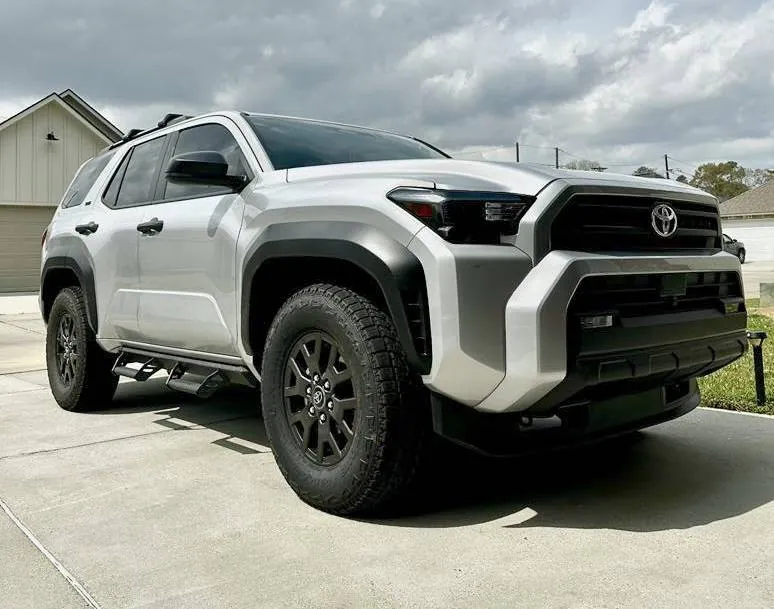 Suspension lift kit components and 33-inch tires on a workbench in a garage.