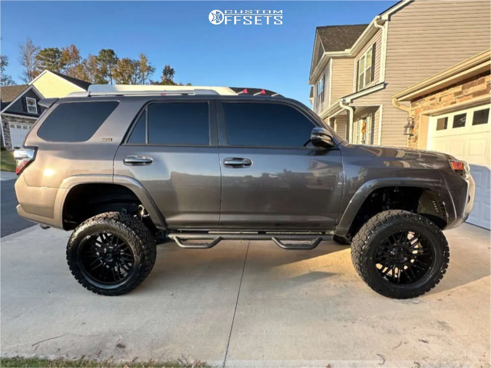 Toyota 4Runner with 33-inch tires on a dirt trail using a jack and tire iron.
